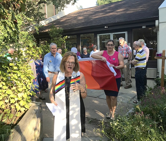 Rev. Dr. Debra W. Haffner, Minister United Universalist Church in Reston, leads church and community members toward the church's entrance off Wiehle Avenue, where they would install the church's new Rainbow flag.