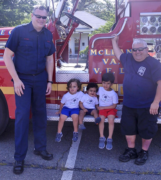 Mark Peters; 3-year-old Arman; 1-year-old Zain; 4-1/2-year-old Rehan Smith; and Mike Paris, McLean Volunteer firefighter, join the Cherrydale Volunteer Fire Department at the beginning of its parade Saturday, July 20.