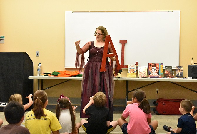 Sign language interpreter Kathy MacMillan teaches the audience a sign for the letter “A.”