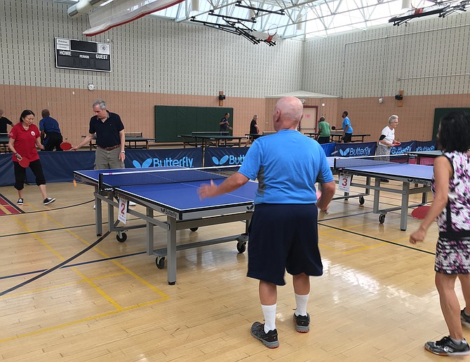 Pauline Jensen, top left, won gold in women’s singles and women’s doubles at the Maryland Senior Olympics Ping Pong Tournament at Potomac Community Recreation Center Saturday, July 27. Here she begins mixed doubles with partner Carl Bumiller playing Mi Kim and Richard Asendorf.