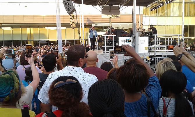 Contemporary Christian music artist Danny Gokey points the microphone at his fans, who help him sing 2016 ballad “Tell Your Heart to Beat Again” at a free concert on a Friday evening July 26 outside Tysons Corner Center shopping mall.