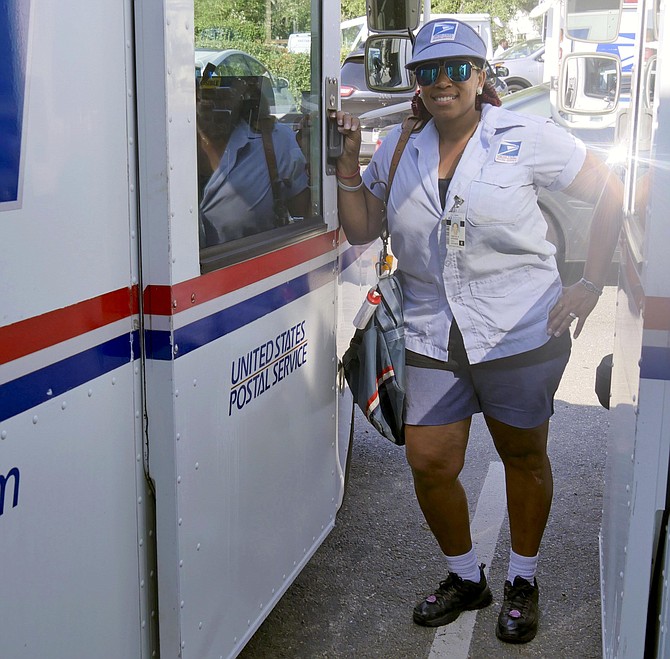 Yvette “E” Stevens stands outside her mail delivery truck after her rescue of an elderly customer on her postal route who fell and lay on his kitchen floor for five days.