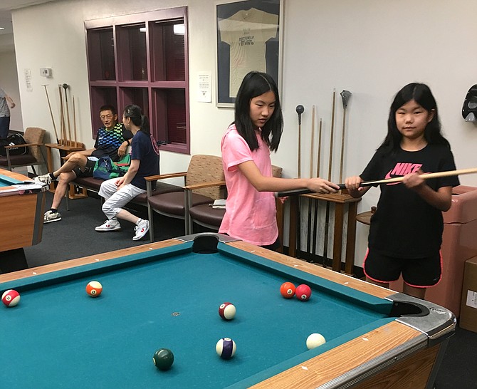 Amy Xu,13, left, and her sister Ellie, 9, practice pool at Potomac Community Recreation Center Friday.