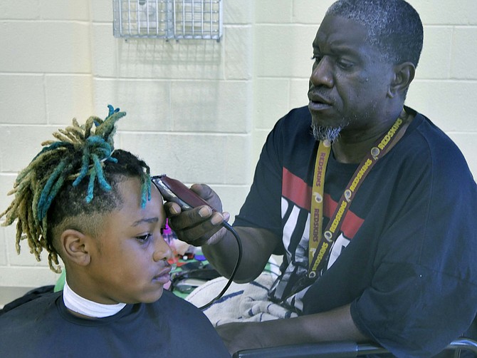 Gary Bailey gives Nehemiah Makins a free haircut at the backpack event at Charles Houston Recreation Center.