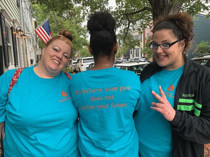 Laura Harrell-Mitchell, center, proudly shows off her t-shirt as fellow residents Ericka Miller and Kayla Landes agree with the slogan “we believe that your past does not define your future.”