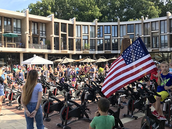 With SUP triathletes, spectators and volunteers looking on, South Lakes High School student Camille Denny, 17, sings the national anthem at the start of the First SUP Triathlon held at Lake Anne Reston on Sunday, Sept. 15, 2019.