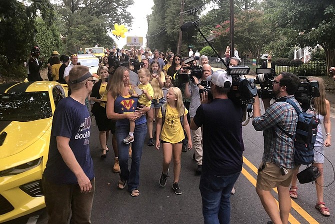 Surrounded by media and well-wishers, Erin Weinburger holds son Whitaker, center, with daughter Lakeland as they walk to Charles Barrett Elementary School on Sept. 11. Whitaker, 4, who loves the yellow Bumblebee character in the “Transformers,” was greeted by more than 100 yellow vehicles in a surprise celebration of his first cancer-free birthday.