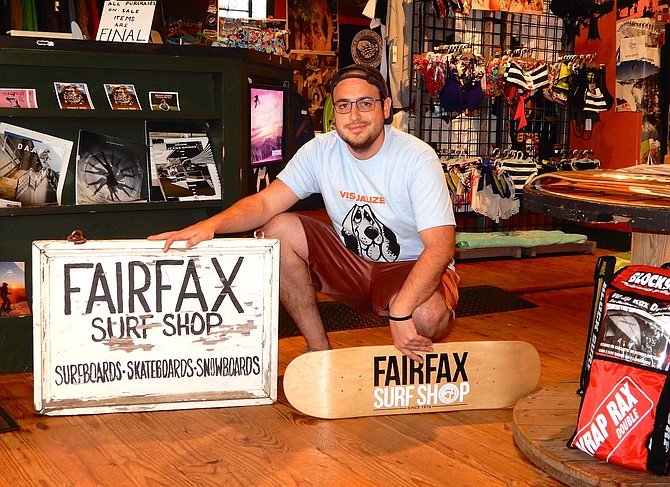 Adam Turrisi poses with the Fairfax Surf Shop’s original sign.