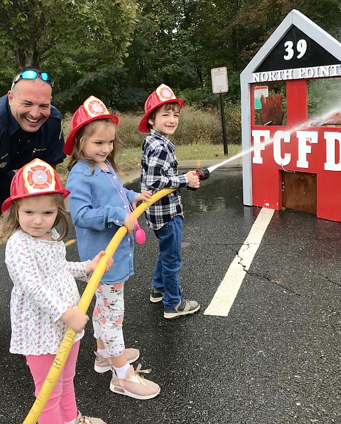 Captain Patrick Sheehan at Station 39 North Point looks over his new recruits, the Damavandy children from Great Falls, Max, 7, and his sisters Layli, 5, and Arya, 3, during Fairfax County Fire and Rescue Department's Open House 2019 at Station 39 North Point that serves Herndon, Reston and Great Falls.