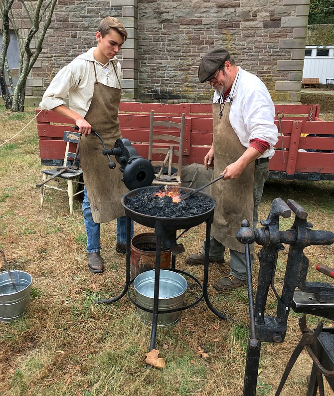 Blacksmith Eric Johnson, right, and apprentice Josiah Bloom demonstrate their craft to visitors at Great Falls Park Sunday.