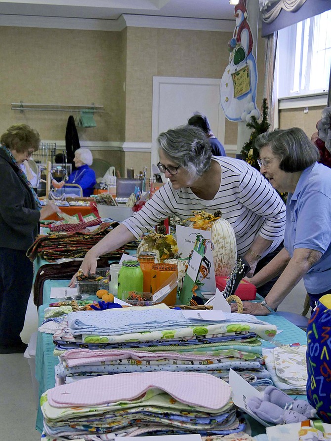 Dennisse Thomas, right, arranges the baby offerings, a hot seller at the Bazaar.