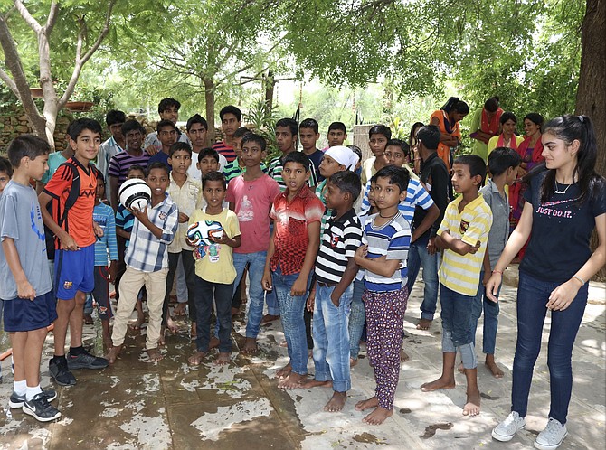 Kushaan (second from left) and Medhnaa Saran (right) visit with the children of Bal Ashram in India.