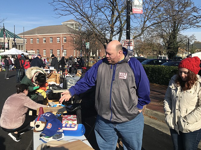 As a possible buyer looks through his items at the Herndon Downtown Community Yard Sale, seller Kirk Denino of Reston explains to Stephanie Moore-Brewer of Herndon Parks and Recreation how he decluttered.