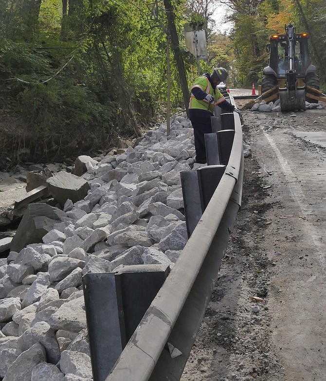 Bulldozers work to restore Chain Bridge Road, which was blown up by a burst water pipe early Friday morning. The pipe burst just under where the bulldozer is working on Saturday morning, blowing the road apart, gushing down the side of the road and taking down the railing.