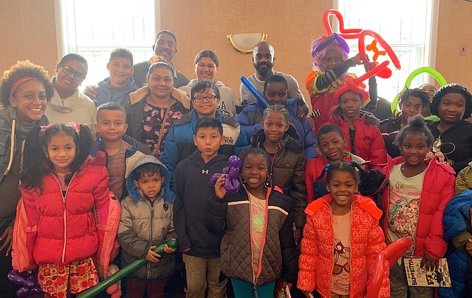 Children from the Charles Houston Recreation Center gather for a photo to show off their new coats at the Nov. 9 coat drive distribution at the Departmental Progressive Club.