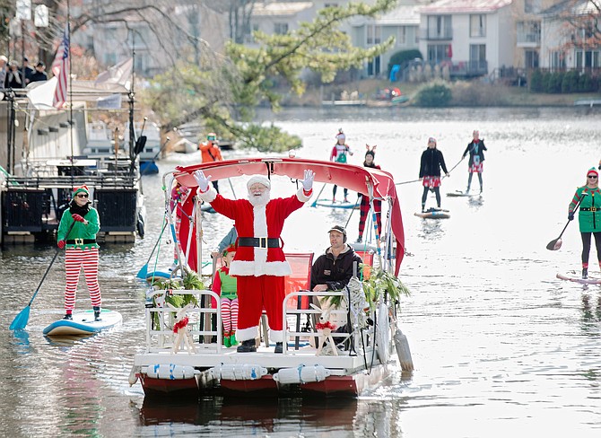 Accompanied by elves on stand up paddle boards, Santa sets course for the Lake Anne Plaza dock, Reston to participate in "Jingle on the Lake."