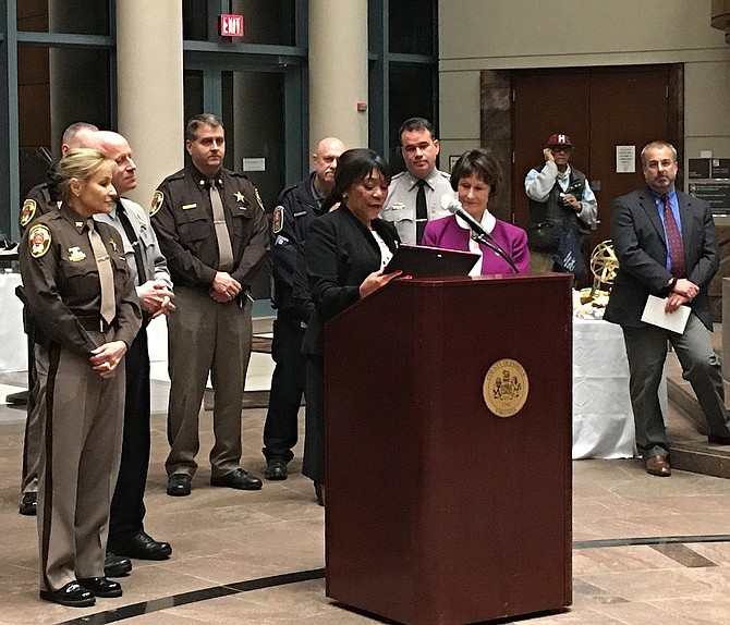 Shirley Ginwright, chairman of the Communities of Trust, presents a plaque to Sharon Bulova (in purple) while law-enforcement personnel, including Sheriff Stacey Kincaid, Police Chief Ed Roessler, MPO Wayne Twombly and Major Dean Lay, look on.