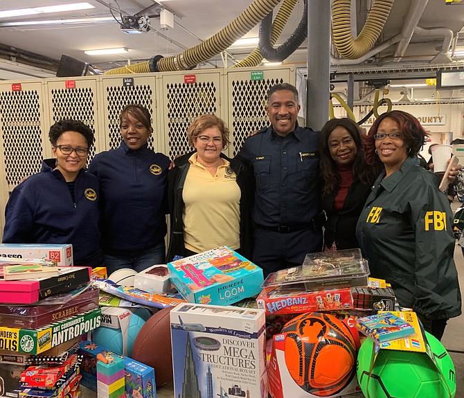 Fairfax County Fire and Rescue Deputy Chief Willie Bailey, third from right, and founder of the annual toy drive, poses with volunteers from the D.C. Field office of the FBI.