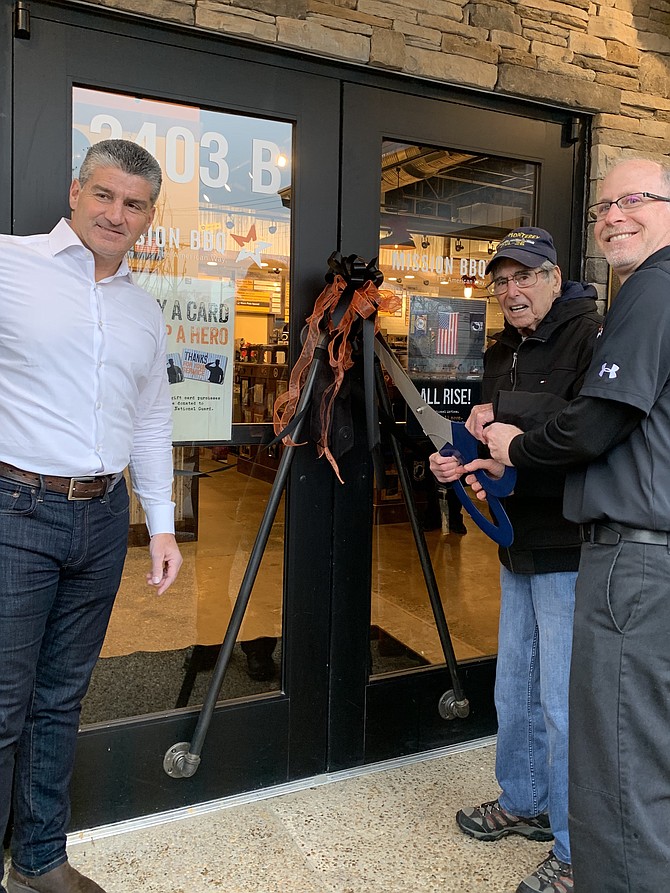 Retired Air Force Colonel Robert A. Shawn takes part in the ribbon-cutting ceremony, celebrating the opening of MISSION BBQ located at 2403B Centreville Road, Herndon, on Dec. 16. Host and co-founder of MISSION BBQ, Bill Kraus, lends support, as does General Manager, Adam Faggio.