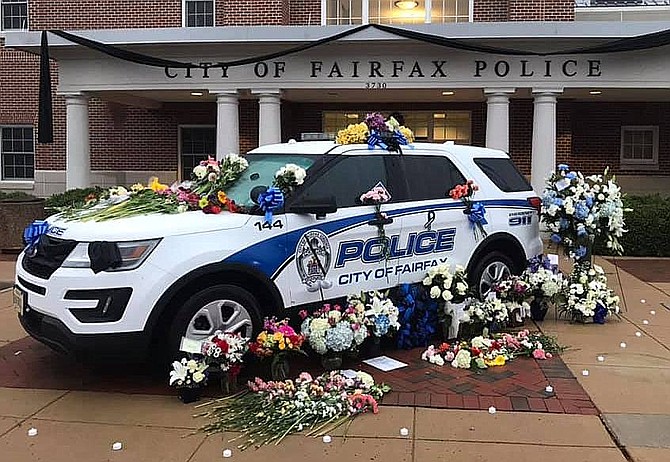 Black bunting is draped across the police station, while a floral memorial adorns this police car in Sgt. Moskowitz’s honor.