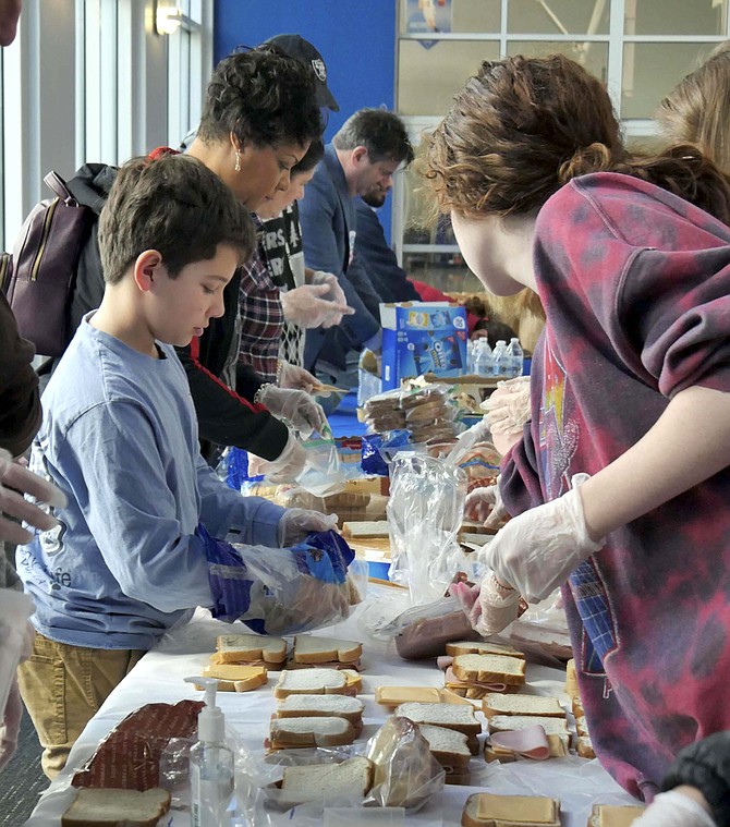 Volunteers of all ages make bologna and cheese sandwiches to fill 200 brown paper bags for delivery to Arlington homeless.