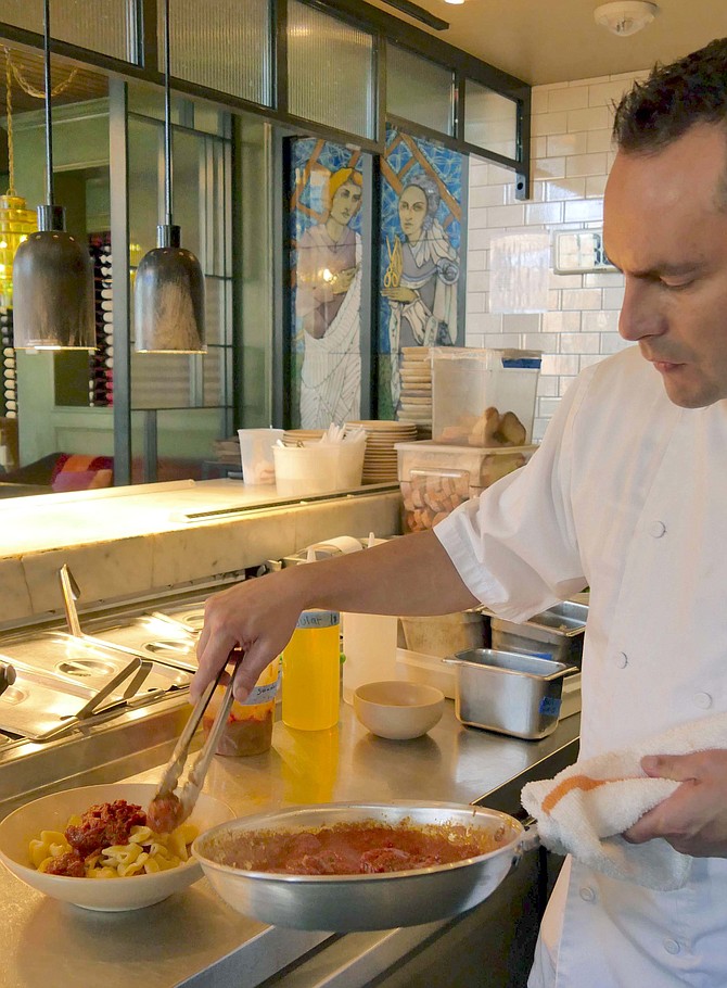 Chef Santiago Lopez placing meats on homemade rigatoni.