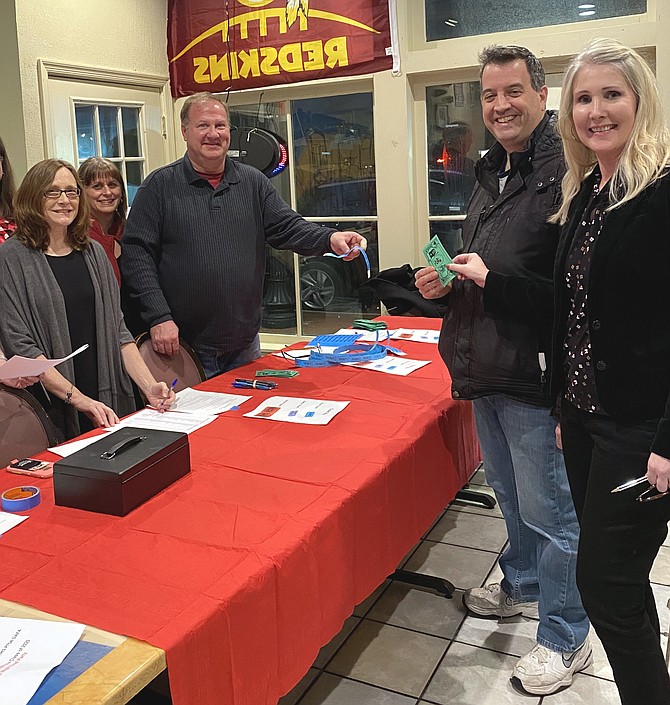 From left: Rosemary DeBenedittis and Joan Koss of Herndon watch as Scott Steiger of Herndon hands Jarrett Goldfedder of Vienna and Susanna Blackman of Herndon their wrist bands, "$25k in Casino Cash" and drink tickets at the annual Casino Night and Silent Auction Fundraiser. The event is a fundraiser by the Herndon High School Class of 2020 All Night Grad (ANG) Committee.