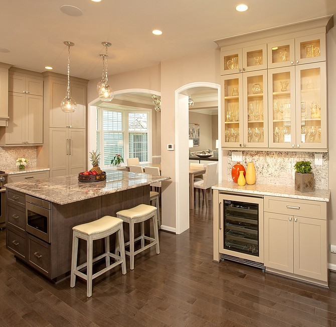 To generate more light and living space in a circa 1990s house, Sun Design Remodeling removed a wall between the kitchen and great room. A granite food prep and dining counter replaces a stand-alone breakfast table. The wine refrigerator is convenient to the re-designed family room.