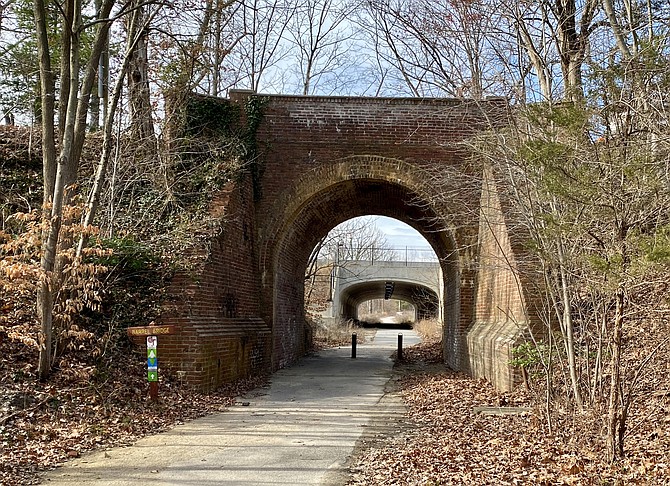 Historic brick and masonry arched bridge built in 1946 outlines the new bridge in the background that replaced it for vehicle traffic.