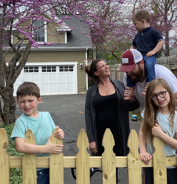 The Spear family of the Town of Herndon, Jay, 5, mom Christin, dad Mike, Zach, 2, and Lily, 5, stay behind the new driveway fence Mike installed. On the other side, a 6-foot social distancing chalk line keeps others a safe COVID-distance away from the family.