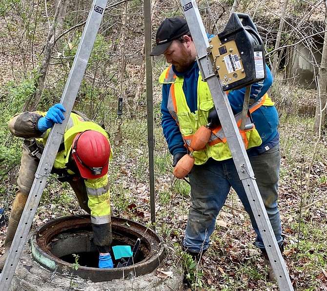 Matthew Moss, of Pennsylvania, and Tom Thompson, of Ohio, lower robot into wastewater pipeline in the Pohick Stream Valley area.