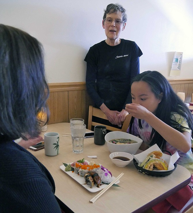Rosie Gordon-Mochizuki, co-owner of Sushi Zen, chats with customers eating in the restaurant before the shutdown.