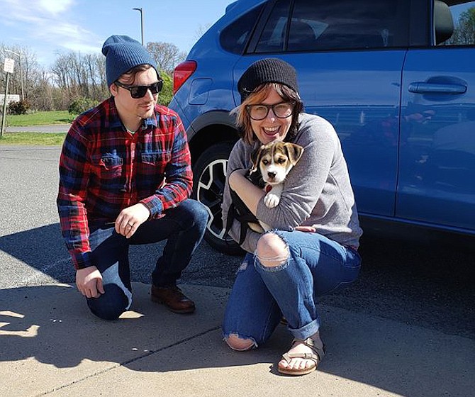 A new puppy, adopted virtually from the Animal Welfare League of Alexandria, makes the day of a couple.