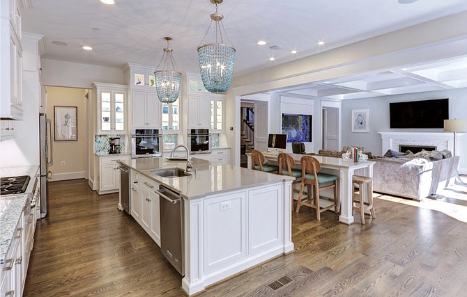 A glass backsplash and beaded pendant lighting are paired with contrasting classic gray Silestone countertops and white cabinets.