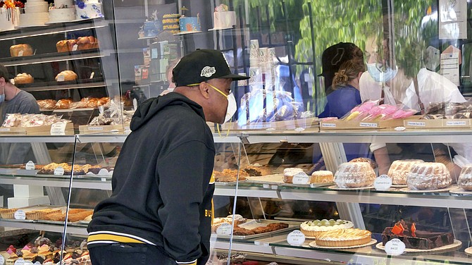 A Randolph’s customer stares through the new plexiglass barriers as he selects his cupcakes for Mother’s Day.