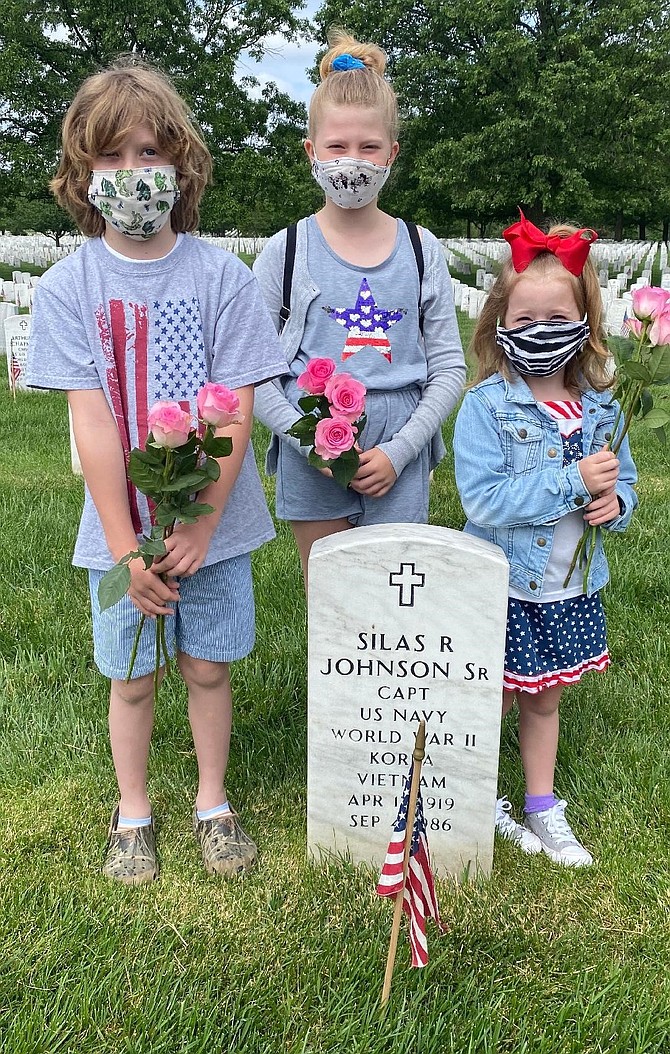 Wearing protective masks, siblings Rory, 8, Sarah, 9, and Norah, 6, Mogle visit the grave of their great-grandfather, Silas Johnson, May 25 at Arlington National Cemetery. Johnson was a Naval Aviator and served in World War II, Korea and Vietnam. His wife, Lucille, is buried with him.