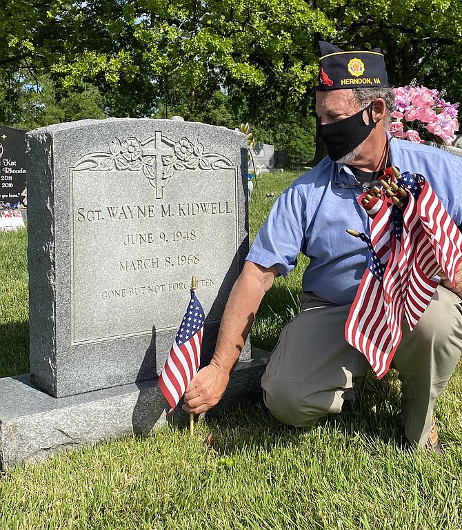 At Chestnut Grove Cemetery in the Town of Herndon for Memorial Day 2020, Michael Cutler, 2nd Vice Commander of The Wayne M. Kidwell American Legion Post 184 Herndon-Reston, adds a remembrance flag to the final resting place for Sgt. Wayne M. Kidwell, United States Army, killed in action during the Vietnam Conflict.