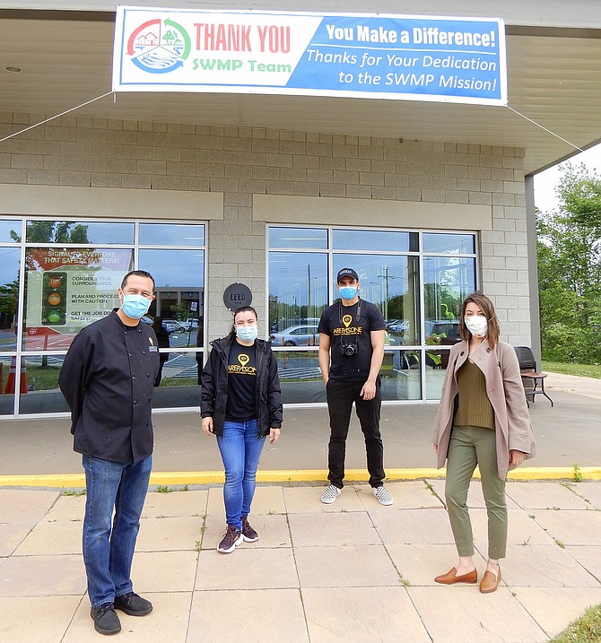 At the I-66 Transfer Station, standing beneath the sign thanking Fairfax County’s Public Works employees are (from left) Ali Arellano, Gabriela Febres and Hernan Rosas of Arepa Zone; and Kim Bryden of Cureate.