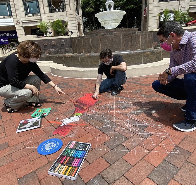 Anne Delaney, Art Reston Executive Director, points out the detail in local artist Ben Morse's chalk art of the Virginia State Bird and Flower, as Morse continues to work and Robert Goudie, Executive Director, Reston Town Center Association, looks on.