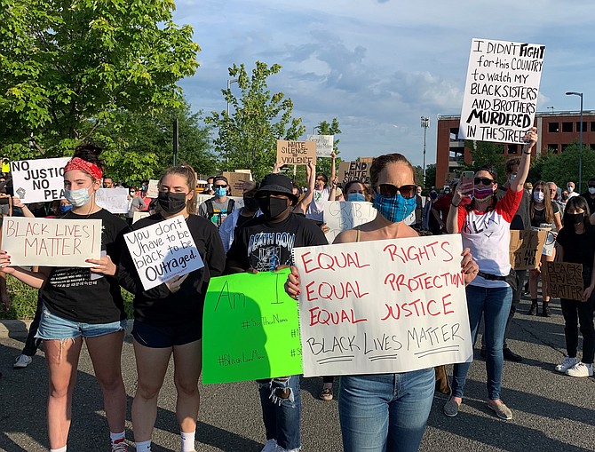 Demonstrators hold signs at the June 2 rally at police headquarters.