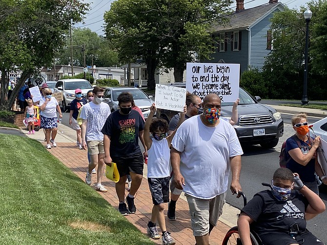 A young boy carries a small sign that reads, "When I Grow Up I Want To Be An Actor Not a Hashtag."