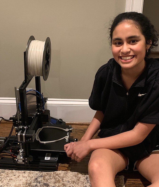 Anisha Talreja of McLean, a TJHSST freshman, poses next to a 3D printing machine the group uses to produce masks.