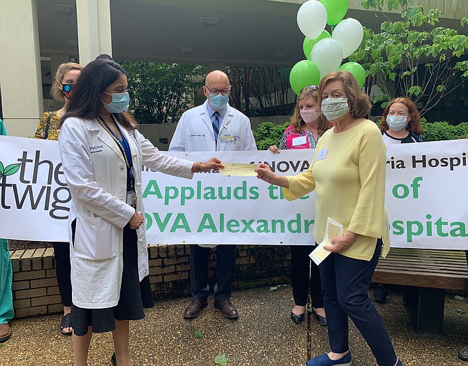 Inova Alexandria Chief Medical Officer Dr. Rina Bansa, left, accepts a check for $100,000 from Twig Junior Auxiliary of Inova Alexandria Hospital treasurer Carol Lyons for the hospital’s COVID-19 Emergency Preparedness fund May 22 at Inova Alexandria Hospital.