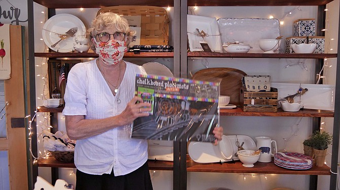 Sandy Gould, co-owner of The Urban Farmhouse on Wilson Boulevard in Arlington, shows a sample of a placemat with crayons donated by customers for the Moms Demand Action Plant Hope book drive for needy families in the community. About 20 were purchased, which “was for a good cause.”