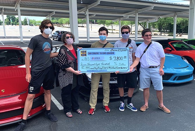 Four organizers of the Car Cruise to End COVID-19 (Andrew Morin of McLean, Eric Mical of Laurel, Tommy Zavrel of Great Falls, and Peter Hayes of Fredericksburg) present a check to Karen Schofield-Leca of the American Nurses Association at FedExField.