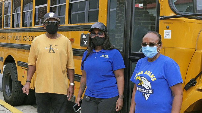 William Roos, Marquetta Lynch, and Zufan Endrais, repurposed school bus drivers, wait outside T.C. Williams for their buses to be loaded with Grab N’ Go breakfasts and lunches for Alexandria school children.