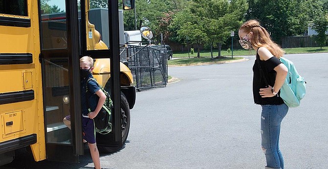 Children model how they will wear masks to board and while on County school buses.