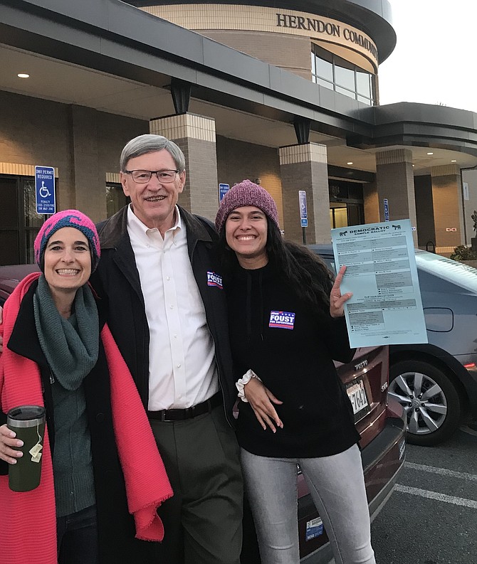 (File photo) Standing with Virginia State Senator Jennifer Boysko (D-33) and Dranesville District Supervisor John Foust (D), volunteer Camila Alfonzo Meza of McLean prepares to distribute an official Commonwealth of Virginia Democratic Sample Ballot to voters at a polling station in Herndon in 2019.