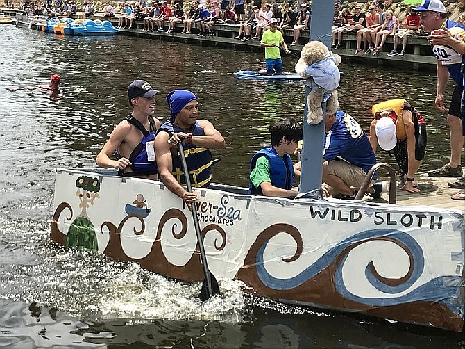 A wake of waves crashes as "River Sea Chocolates Wild Sloth" docks at the pier during the 2018 Lake Anne Cardboard Boat Regatta.