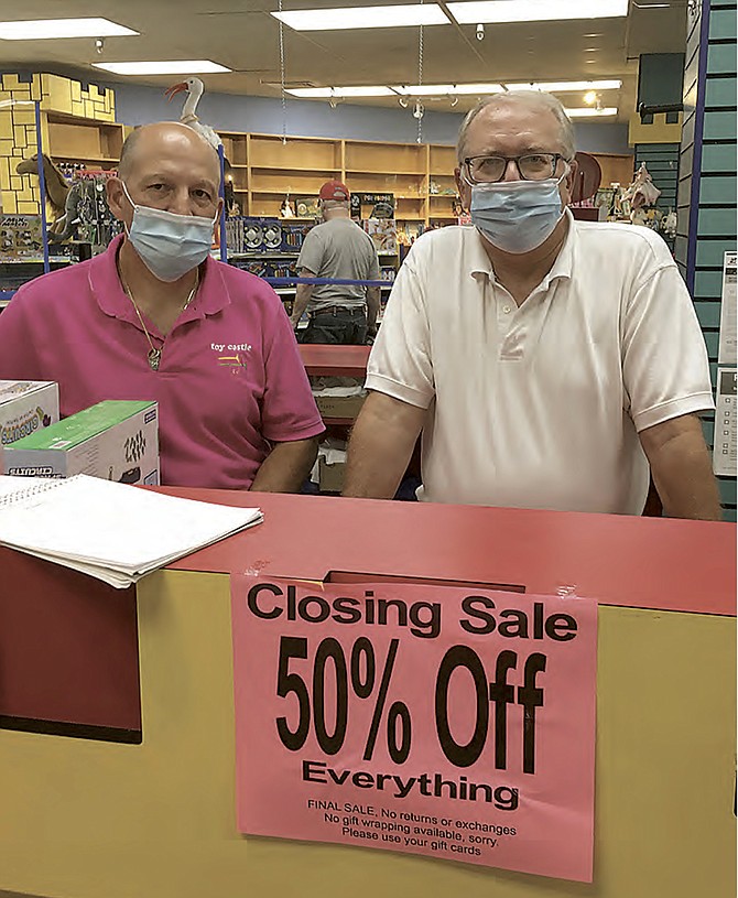 Owners Carlos Aulestria and Brian Mack at the checkout counter of Toy Castle in Cabin John Shopping Center. After more than 40 years, the store will close Aug. 12.